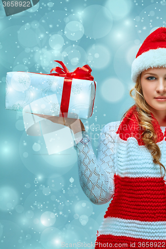 Image of Girl dressed in santa hat with a Christmas gift 