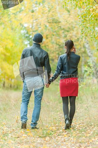 Image of Affectionate couple taking walk in autumn park
