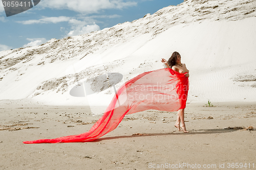 Image of Attractive naked girl with red scarf on sand