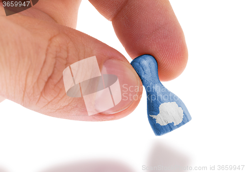 Image of Hand holding wooden pawn, flag painting, selective focus