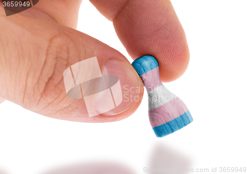 Image of Hand holding wooden pawn, flag painting, selective focus