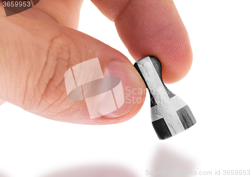 Image of Hand holding wooden pawn, flag painting, selective focus