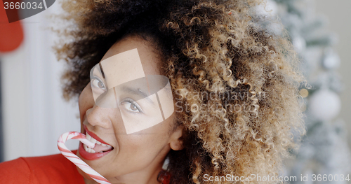 Image of Sensuous young woman licking a striped candy cane