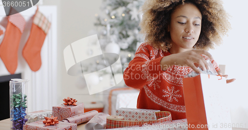 Image of Pretty young woman wrapping Xmas presents
