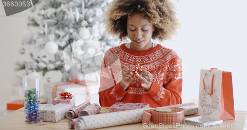 Image of Happy young African woman wrapping presents