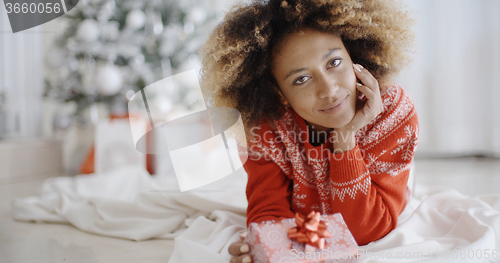 Image of Thoughtful young woman with a Christmas gift