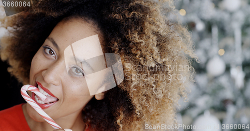 Image of Sensuous young woman licking a striped candy cane