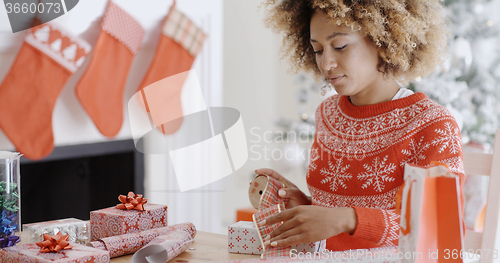 Image of Pretty young woman wrapping Xmas presents