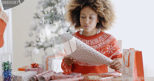 Image of Happy young African woman wrapping presents
