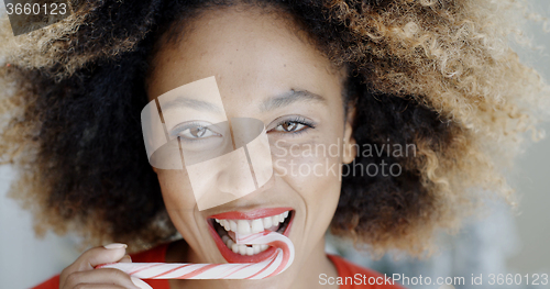 Image of Young woman biting a festive candy cane