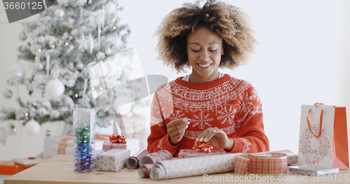 Image of Happy young African woman wrapping presents
