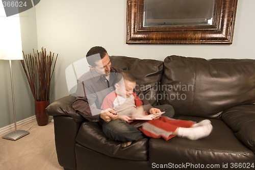 Image of Father and Son Reading a Book on the Couch