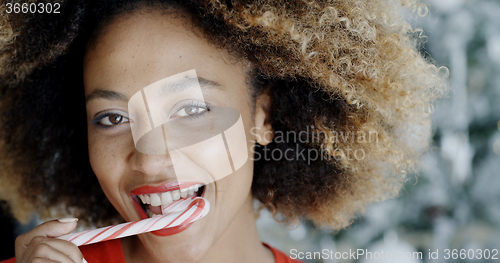 Image of Young woman biting a festive candy cane