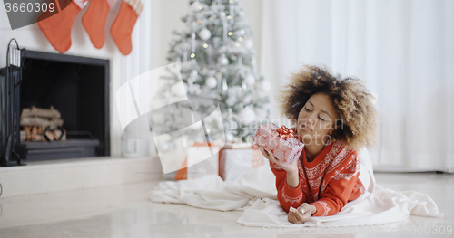 Image of Young African girl lying looking at her Xmas gift