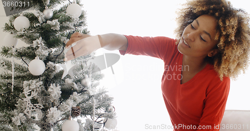 Image of Pretty young African woman decorating an Xmas tree