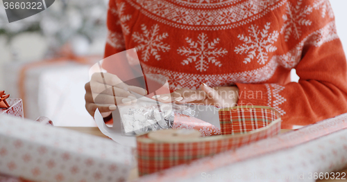 Image of Young woman carefully wrapping a Christmas gift