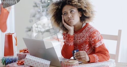 Image of Young woman pondering over an online purchase
