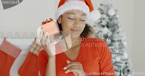 Image of Curious young woman shaking her Christmas gift