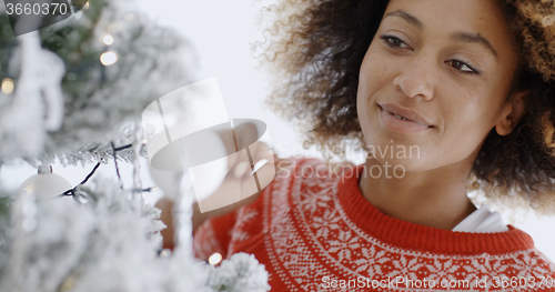 Image of Pretty young woman decorating a Christmas tree