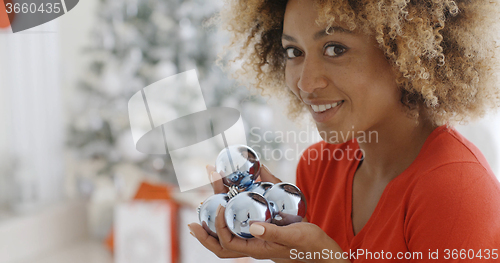 Image of Young woman carrying a handful of Xmas decorations