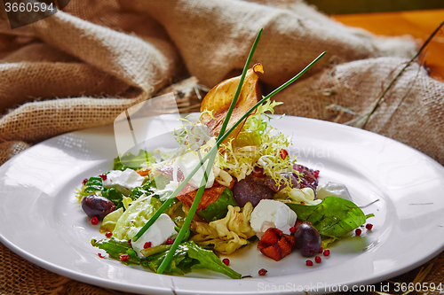 Image of Fresh spring salad with feta cheese, red onion in white bowl. 