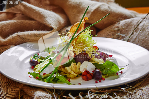 Image of Fresh spring salad with feta cheese, red onion in white bowl. 