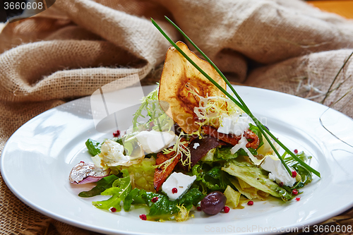 Image of Fresh spring salad with feta cheese, red onion in white bowl. 