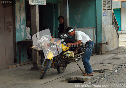 Image of Asian man with motorbike.