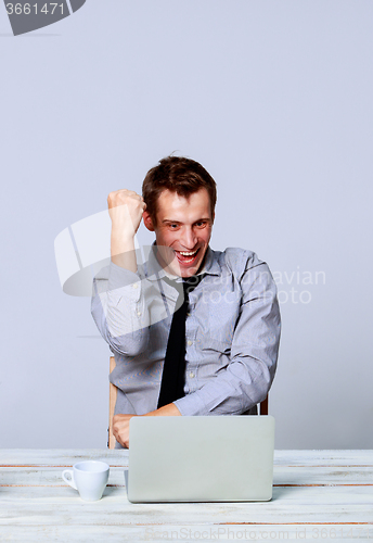Image of Happy man working on laptop in the office