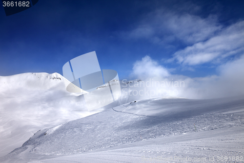 Image of Ski slope with snowmobile trail and mountains in mist at nice da