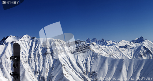 Image of Panoramic view on snowy mountains and snowboard