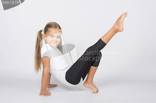 Image of An aspiring gymnast pulls his right leg resting on the hands and fingers of the left leg