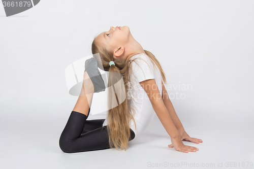 Image of Girl gymnast performs exercises toes touching head