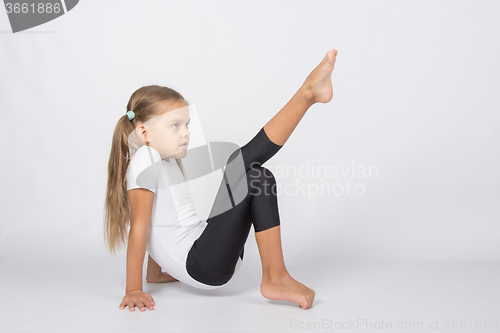 Image of An aspiring gymnast trying to pull his left foot resting on the hands and fingers of the right foot