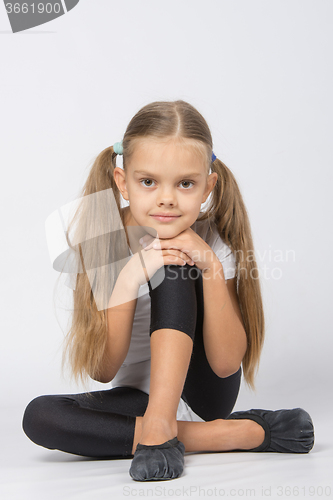 Image of Girl gymnast sitting on the floor with his pen on his knee