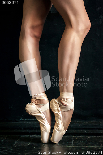 Image of Close-up ballerina\'s legs in pointes on the black wooden floor 