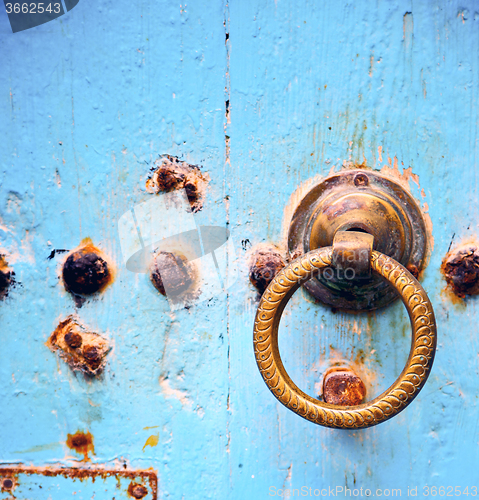 Image of rusty metal   nail dirty stripped paint in the blue wood door an