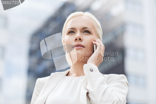 Image of serious businesswoman with smartphone outdoors