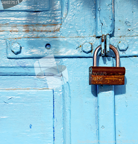 Image of rusty metal     nail dirty stripped paint in the blue wood door 