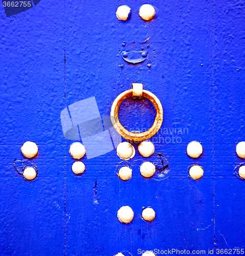 Image of rusty metal     nail dirty stripped paint in the blue wood door 