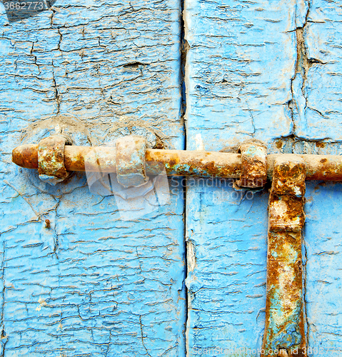 Image of rusty metal     nail dirty stripped paint in the blue wood door 