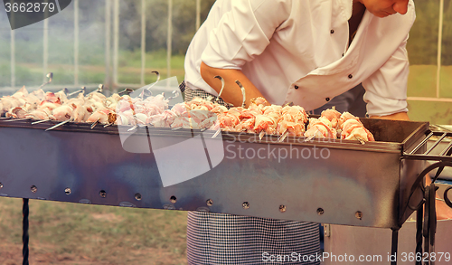 Image of People at work: a man grilling shashlik on the grill.
