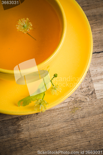 Image of Yellow cup with linden tea on the table
