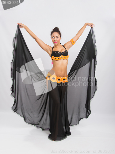 Image of Young girl mulatto dancing in a long black dress candid