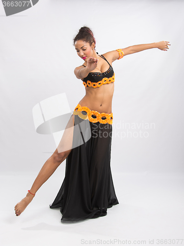 Image of Young girl mulatto dancing in a long black dress candid