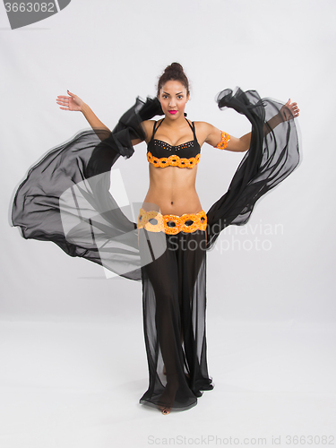 Image of Young girl mulatto dancing in a long black dress candid