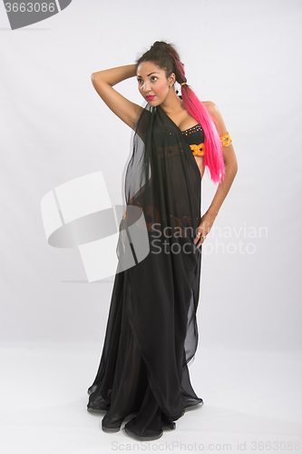 Image of Young girl mulatto dancing in a long black dress candid