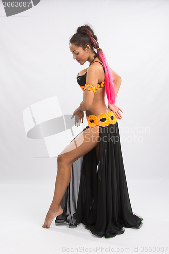 Image of Young girl mulatto dancing in a long black dress candid