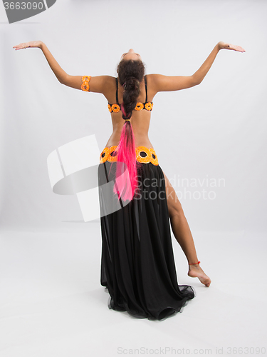 Image of Young girl mulatto dancing in a long black dress candid