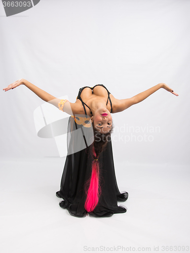 Image of Young girl mulatto dancing in a long black dress candid